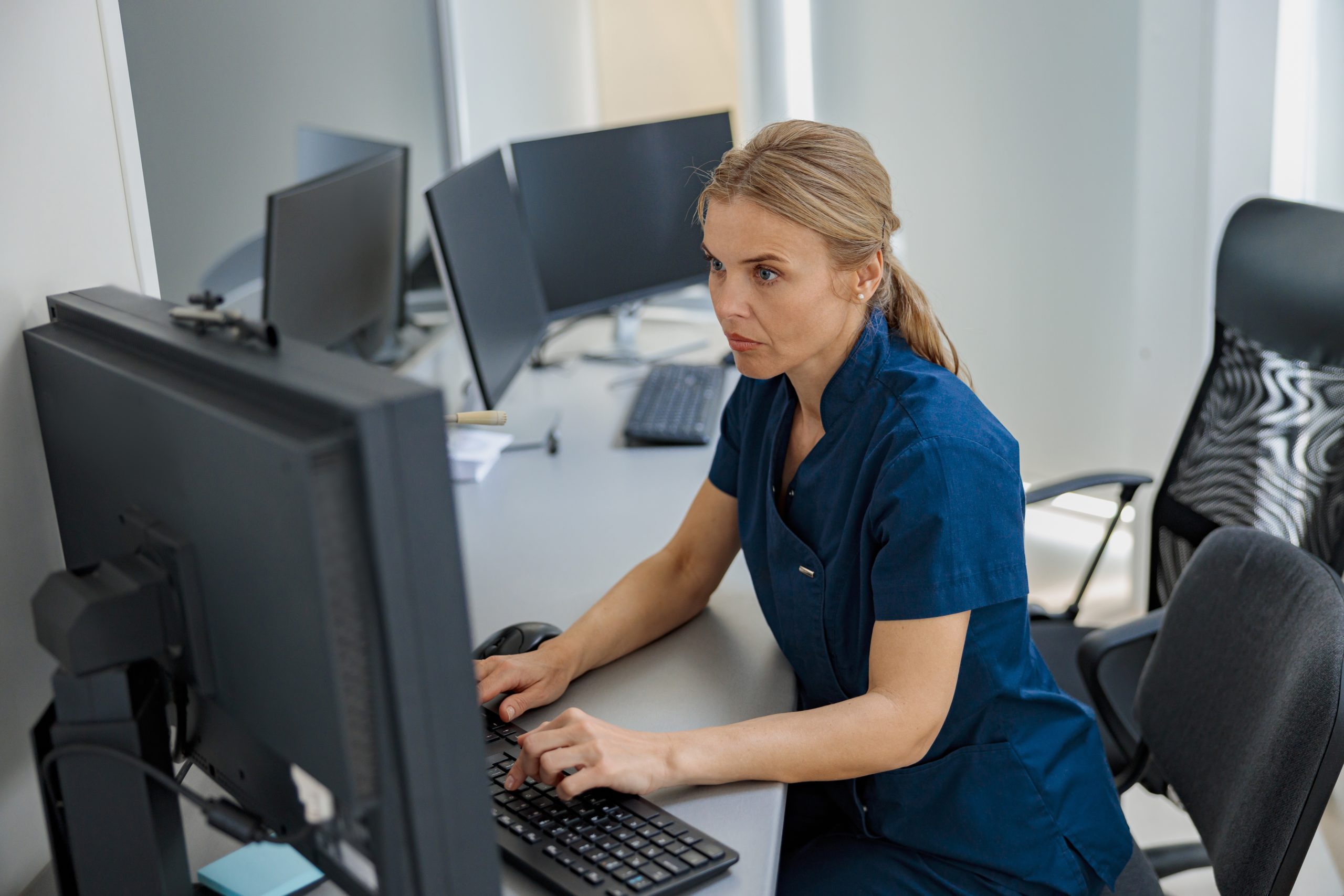 Clinician in dark blue scrubs at computer