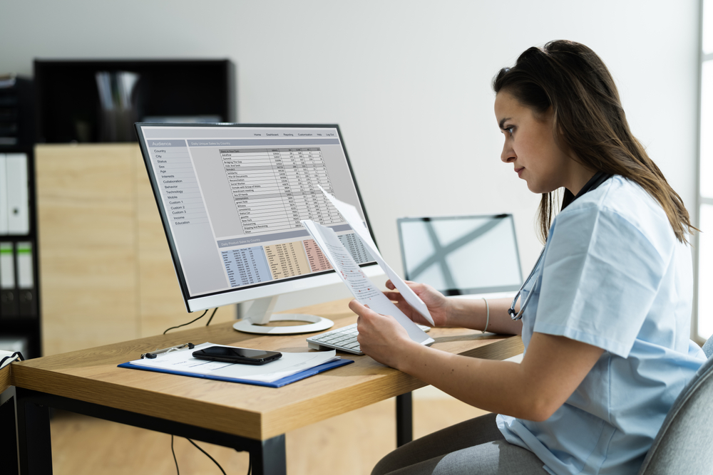Woman in light blue scrubs working on remote monitoring billing codes