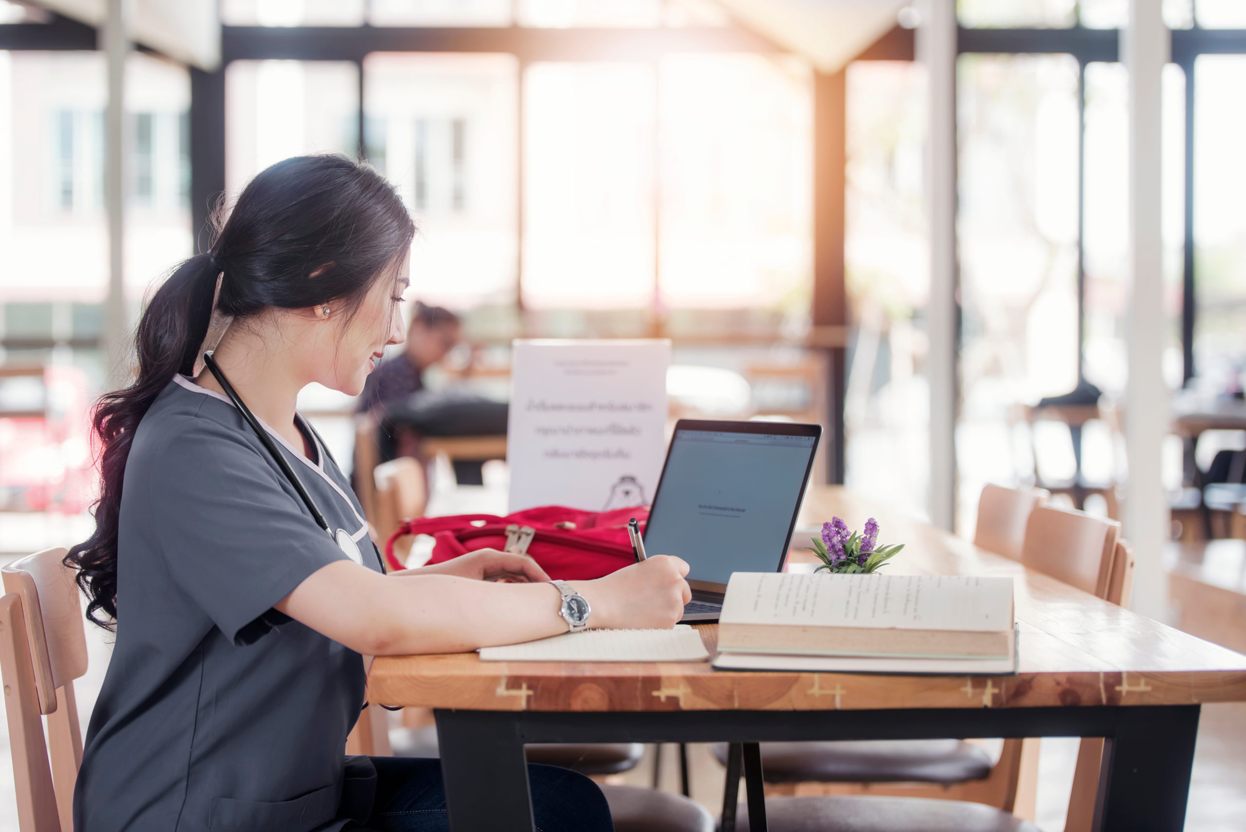 Female clinician studying with laptop and books